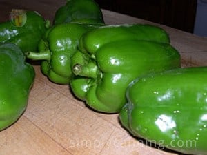 Green bell peppers sitting on a cutting board.