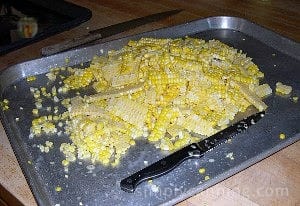 Slicing corn off the cobs onto a cookie sheet.