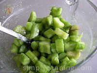 Juicy green rhubarb pieces coated with dissolved sugar in a bowl.