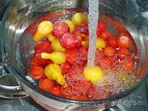 Running water over a bowl of frozen cherry and pear tomatoes.