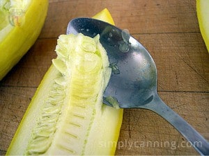 Scooping seeds out of the zucchini spear using a spoon.