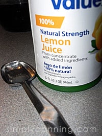 A bottle of 100% natural strength lemon juice with a teaspoon sitting beside it.