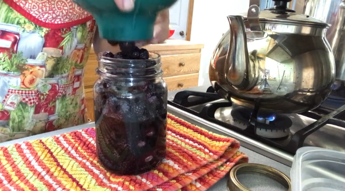 Filling a jar with black raspberries.