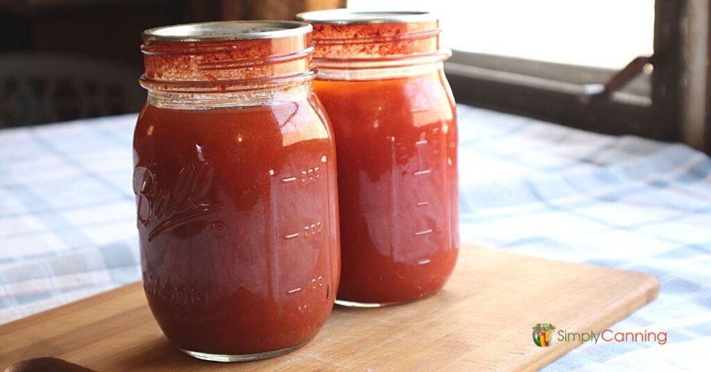 Two pint jars of tomato vegetable juice sitting on the deck railing, demonstrating what the final product will look like.