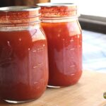 Two pint jars of tomato vegetable juice sitting on the deck railing, demonstrating what the final product will look like.