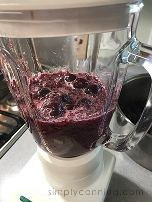 Blending cherries in a blender until smooth.