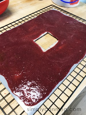 Deep red cherry puree spread evenly over a dehydrator sheet.