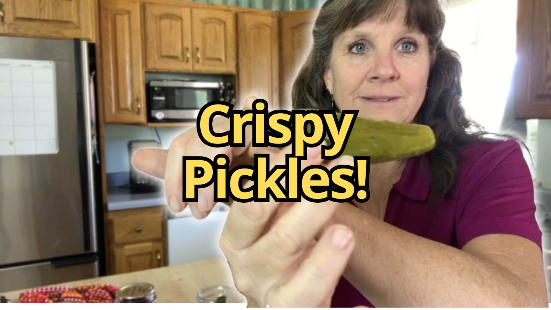 Sharon holding a crisp dill pickle in the kitchen.