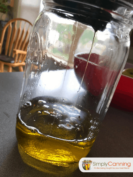 Pouring dandelion salve liquid into a jar.
