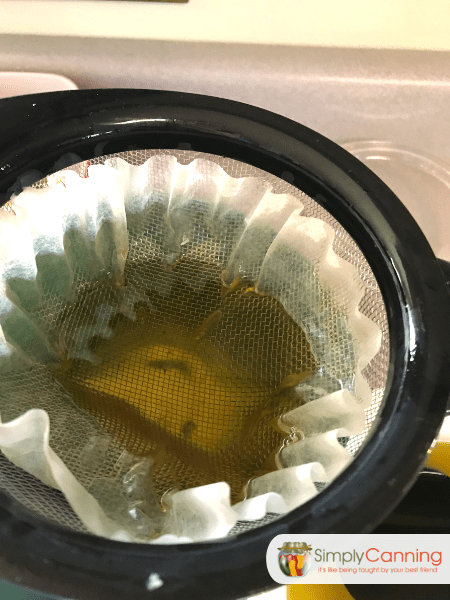 Straining the infused oil through a coffee filter.