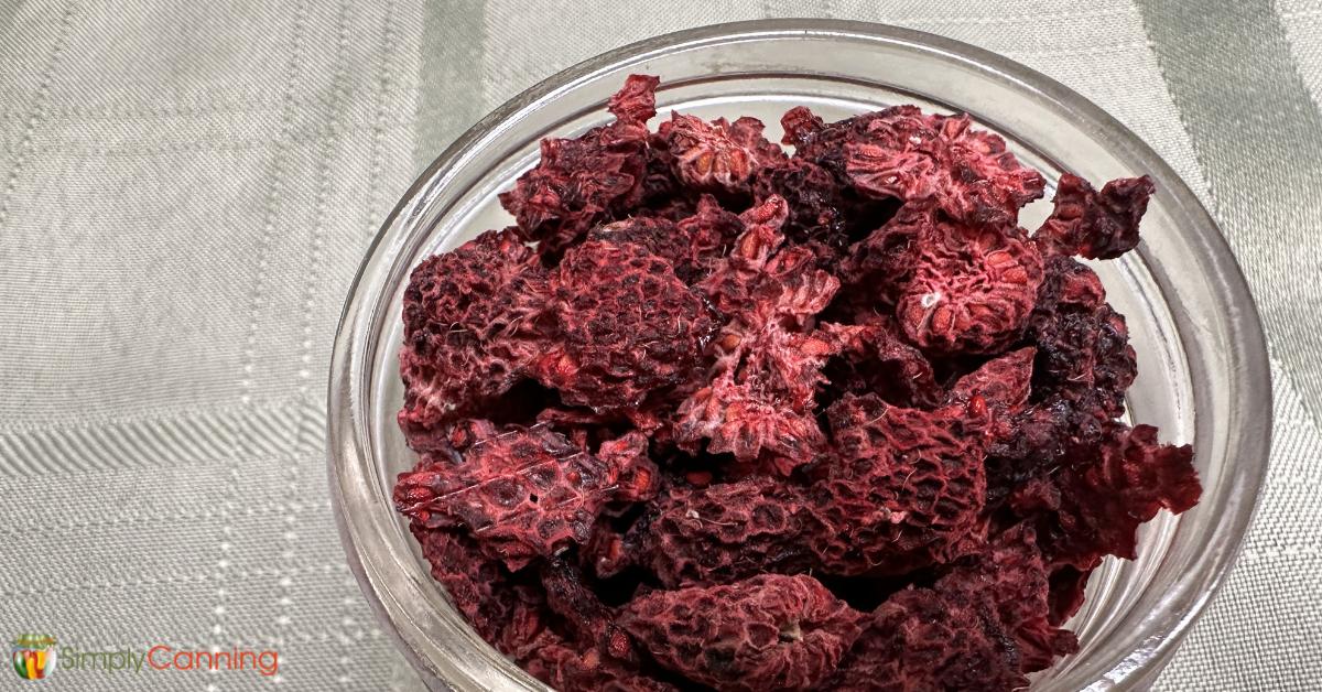 A clear glass dish filled with flat, crispy dried raspberries.