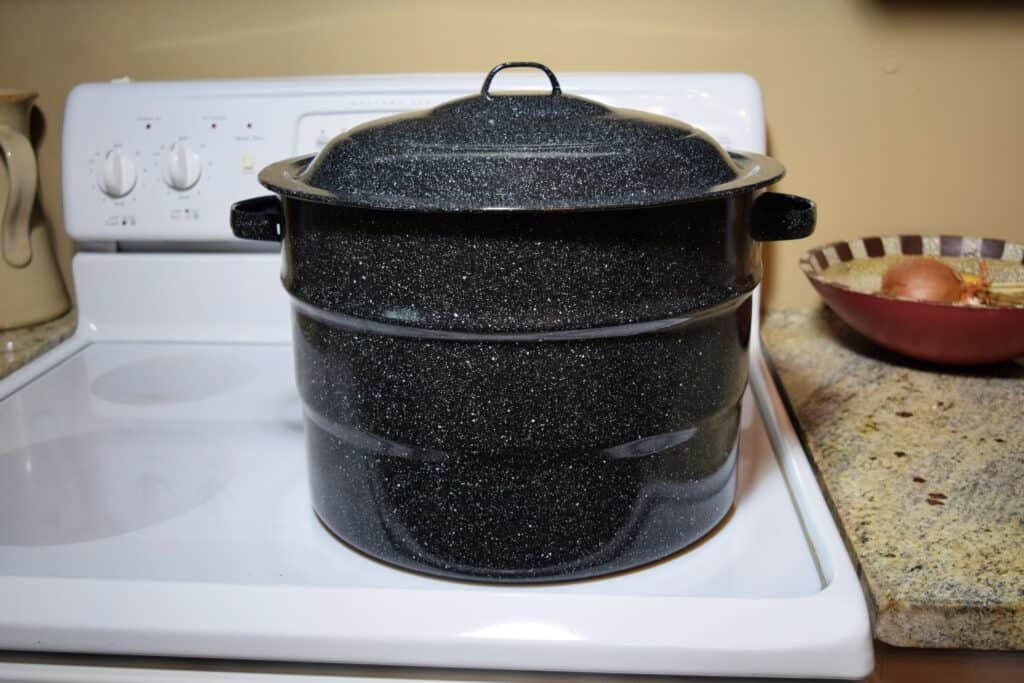 Speckled graniteware canner sitting on a white glass top stove.