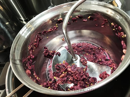 Running fresh grapes through the crank food mill to remove the skins and seeds.