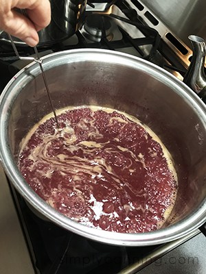 Sharon stirring a boiling pot of grape jam.