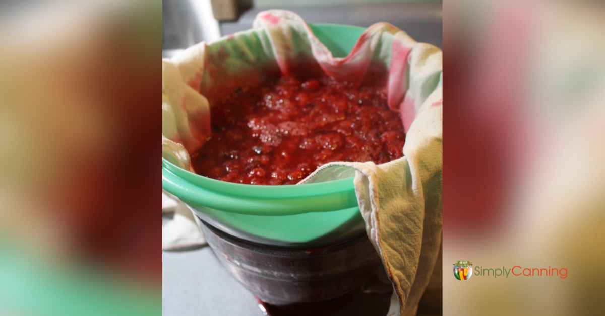 Straining cranberry pulp through a tea towel-lined strainer.