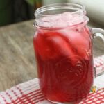 A drinking jar filled with ice and bright red cranberry juice.