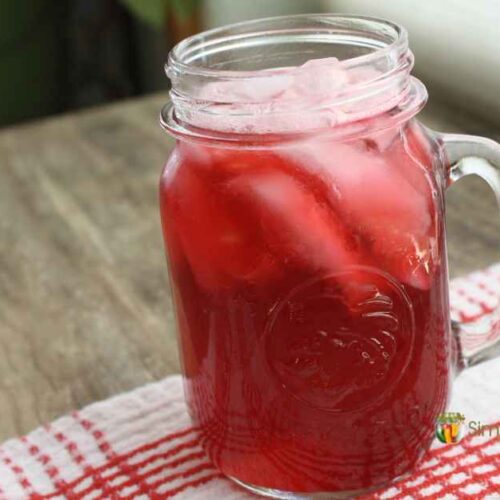 A drinking jar filled with ice and bright red cranberry juice.