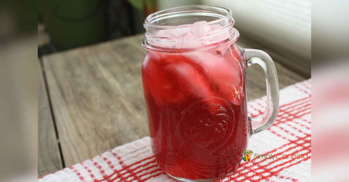A drinking jar filled with ice and bright red cranberry juice.