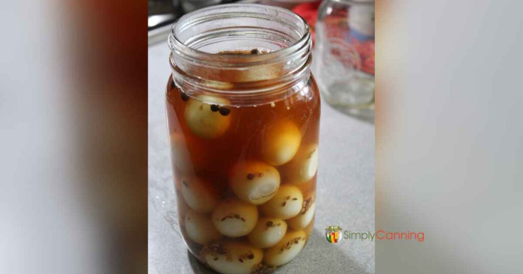 A jar filled with hard boiled quail eggs covered with spicy brine