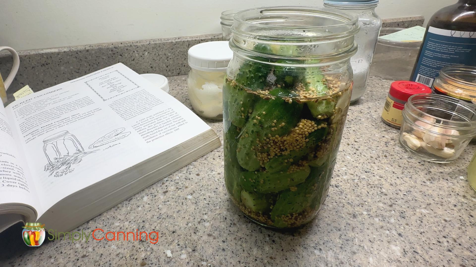 Quart jar of cucumber pickles with the Nourishing Traditions book next to it.