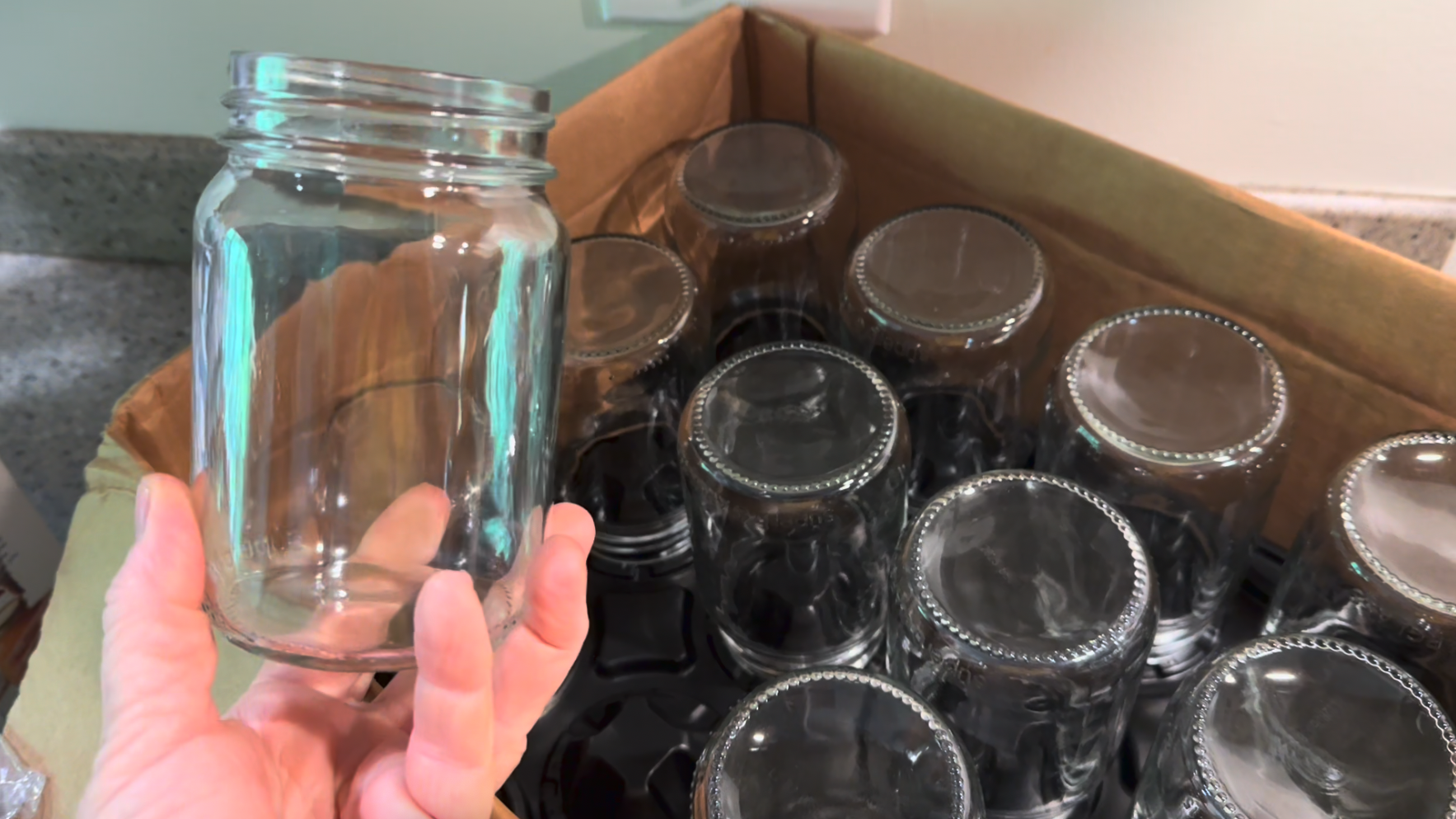 Hand holding a Superb pint canning jar in front of a box of pint jars.  