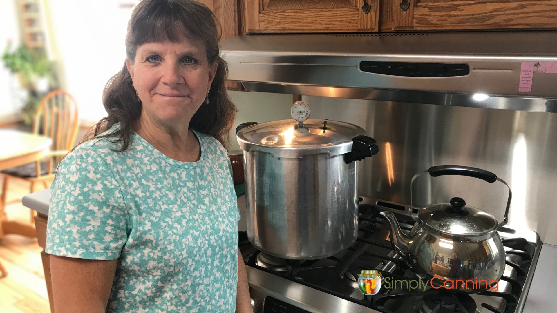 Sharon standing in front of her stove smiling and saying Hi!