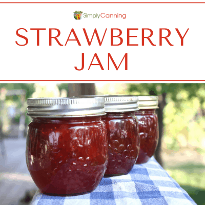 Jars of strawberry jam lined up on a blue and white checkered towel.