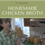 Sharon holding a quart jar of home canned chicken broth with other jars of broth beside her.