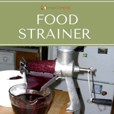 Fruit being pushed through a food strainer.