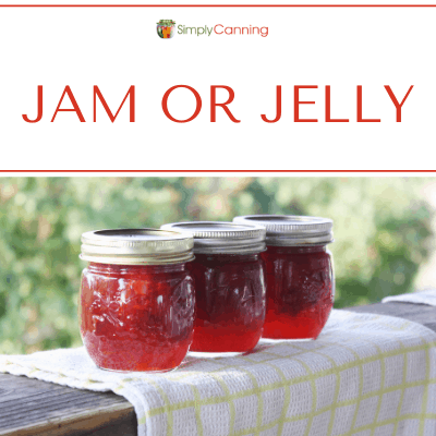 3 jars of jam setting on the deck railing shining in the sun.