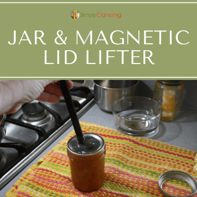 Using the magnetic lid lifter to set a flat lid on top of a jelly jar.