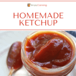 A small jar filled with thick homemade ketchup with a spoon sitting on the side.