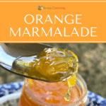 Orange marmalade running off of a spoon over a jar of marmalade.