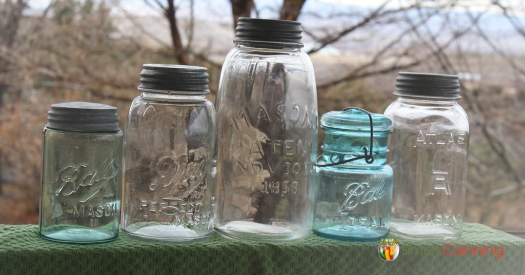 Blue and clear glass antique canning jars sitting outdoors.