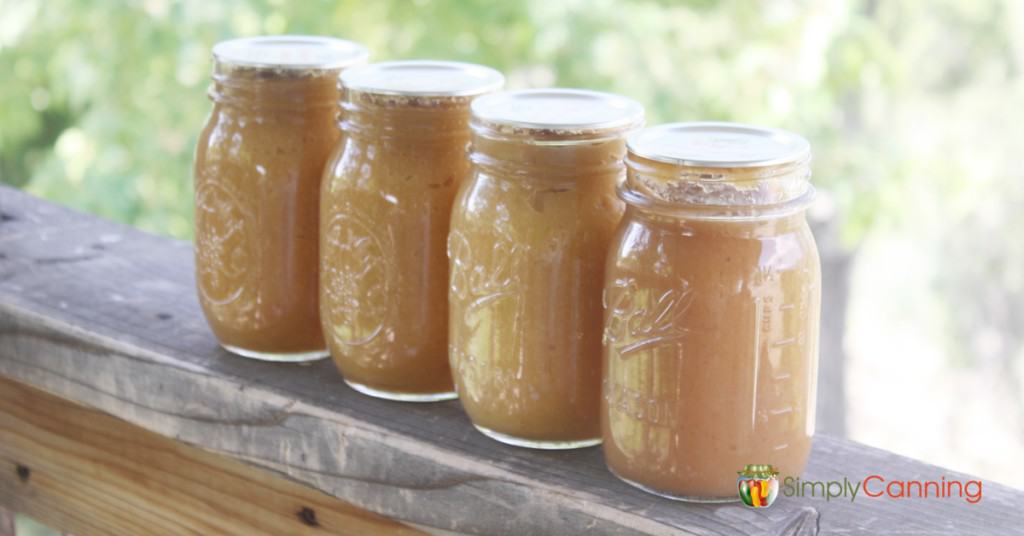 Four jars of applesauce lined up in a row.