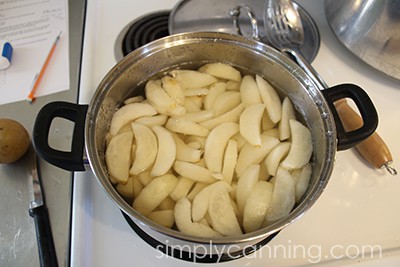 Heating Asian pear slices in a pot of syrup.
