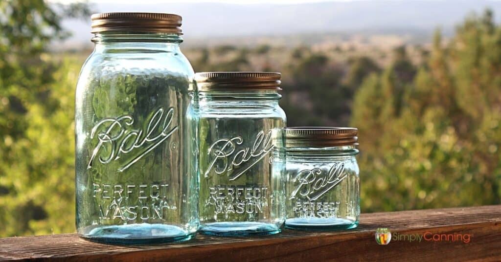 Three blue canning jars with Ball logos on them.