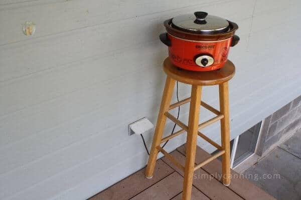 A red Crockpot sitting on a stool outside.
