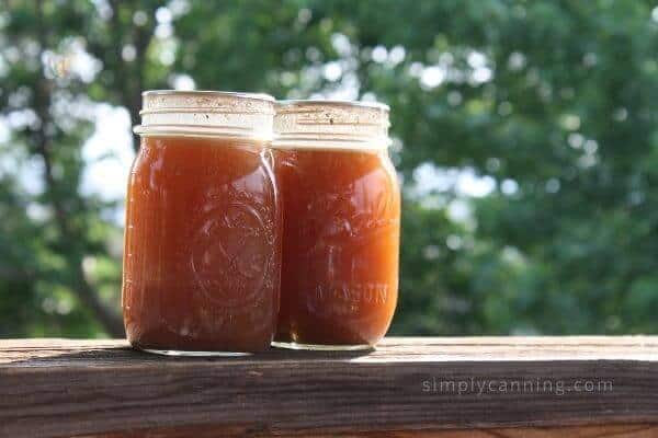 Two jars of home canned beef broth sitting outside.