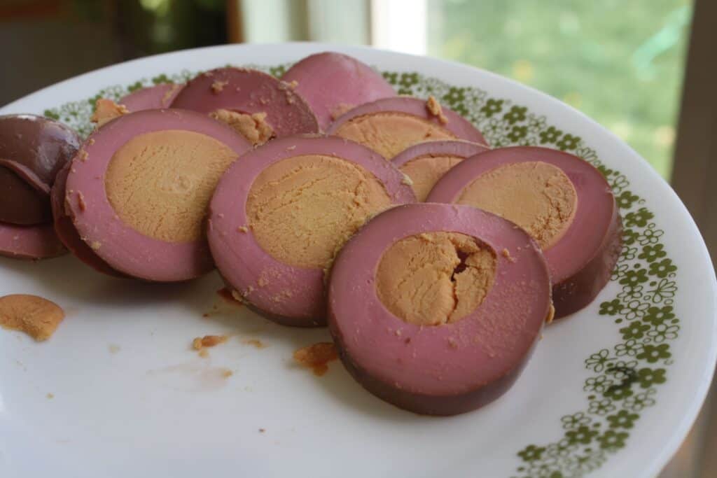 Slices of red colored pickled eggs on a plate.