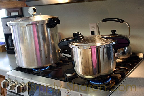 Presto pressure canner sitting next to a smaller pressure cooker on the stove.