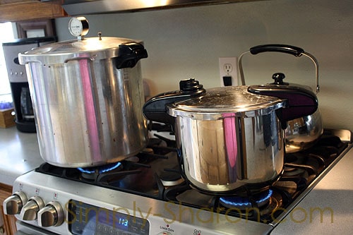 A pressure canner and pressure cooker sitting side by side on the stovetop.