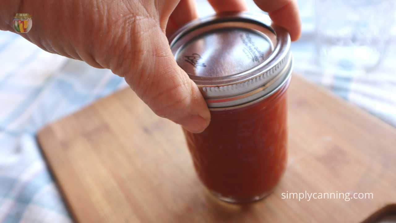 Close up of a 1/2 pint jar of tomato juice ready to go in the canner.