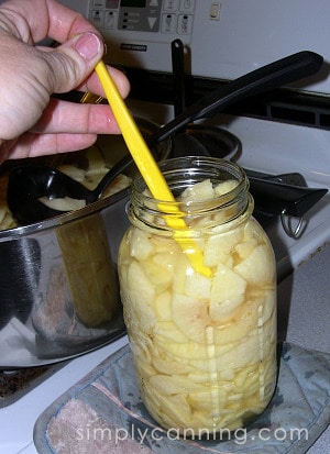 Removing air bubbles from a jar of apple slices.