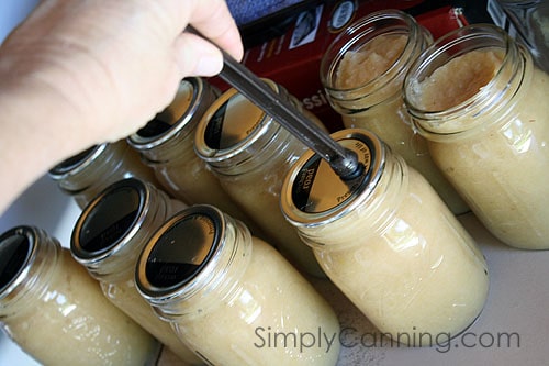 Placing flat lids on top of the applesauce jars.