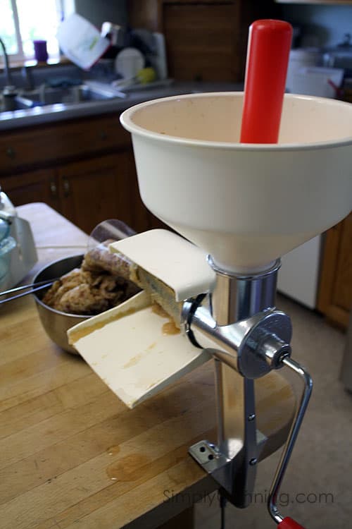 Another view of the applesauce being pushed through the food mill to remove seeds and skins.