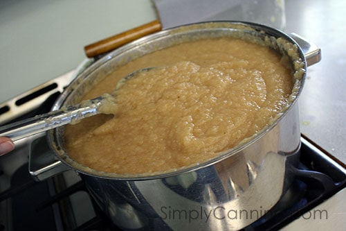 Stirring a pot of homemade applesauce that's cooking on the stove.