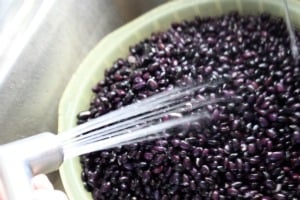 Rinsing off black beans in a colander.