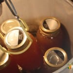 Putting full jars of broth into the pressure canner using a jar lifter.