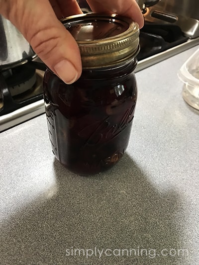 Screwing on the lid on a jar of cherries.